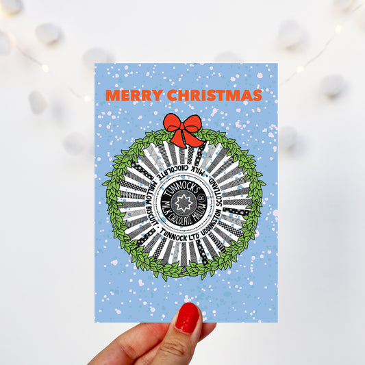 blue Christmas card with a festive tunnocks tea cake