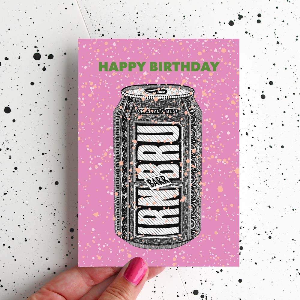 A Pink Greetings Card with an Illustration of an Irn Bru can on it being held over a speckled background