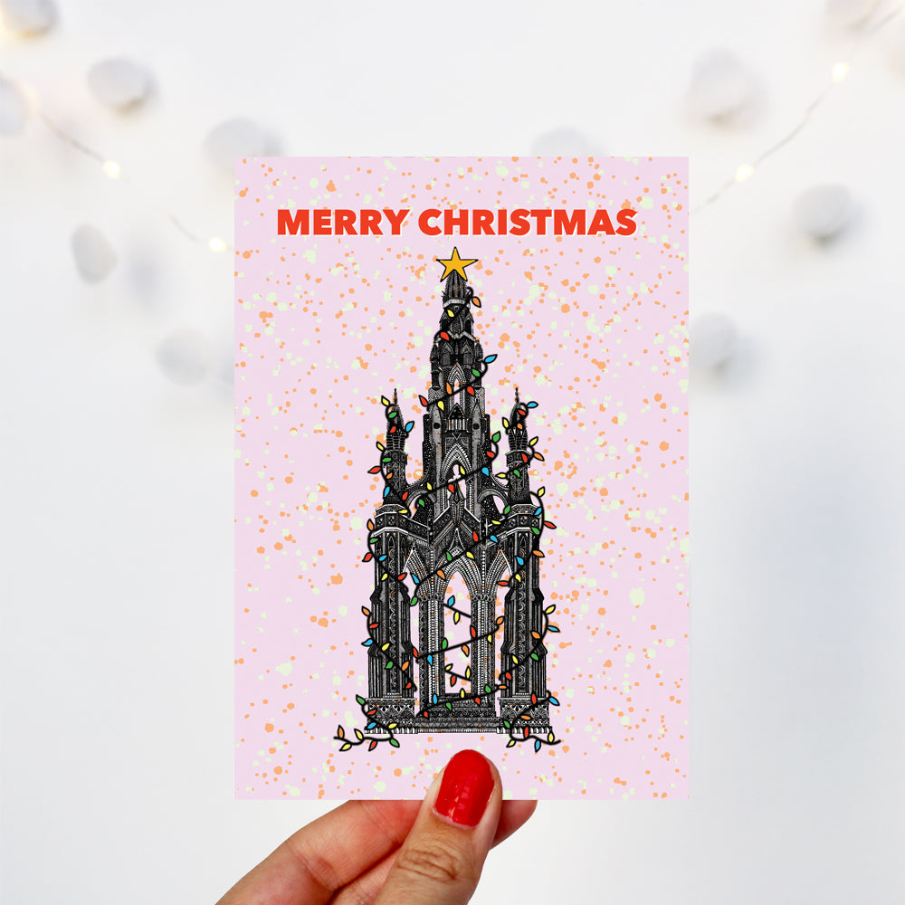 pink Christmas card with the Scott monument in Edinburgh wrapped in lights